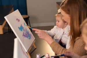 Parent and toddler painting together at an easel