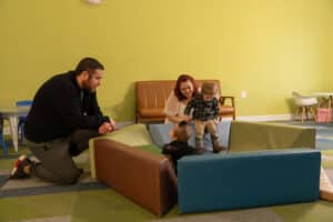 Parents and a young child playing together in a community play area