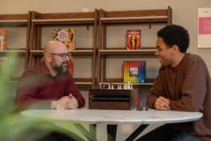 Two neighbors talking at a table in a community lounge