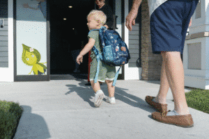 Toddler with a backpack walking into a childcare center